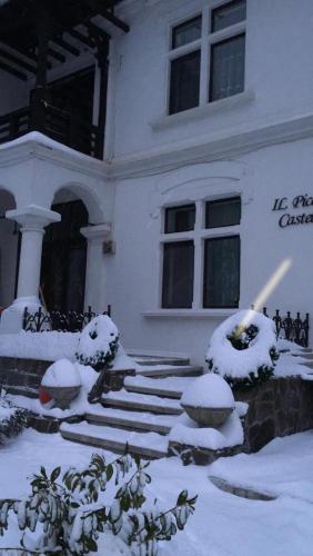 a house covered in snow in front of it at IL Piccolo Castello Busteni in Buşteni