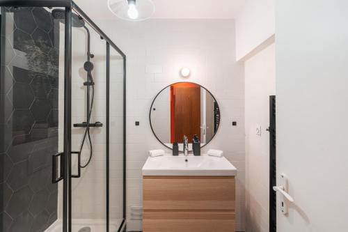 une salle de bain avec un lavabo et un miroir dans l'établissement SERENERS - Charming Serviced Apartments - Beaugrenelle, à Paris