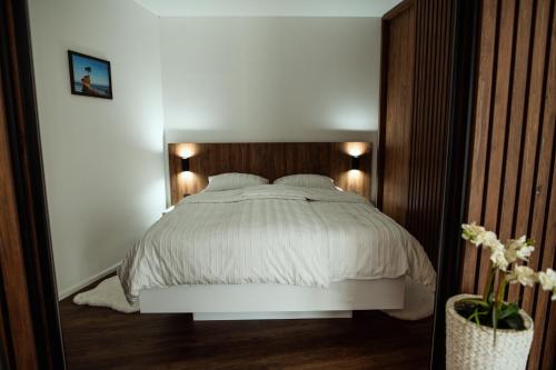 a bedroom with a white bed with a wooden headboard at Anur Apartment in Ptuj