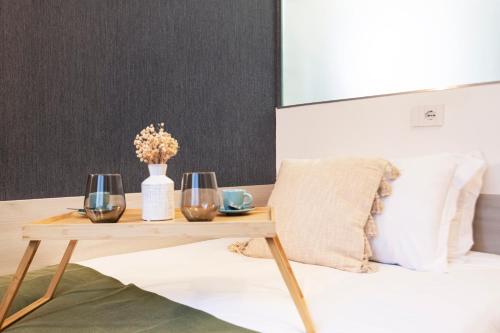 a table with two wine glasses and a vase on a bed at Easylife - FL Suite in Centrale in Milan