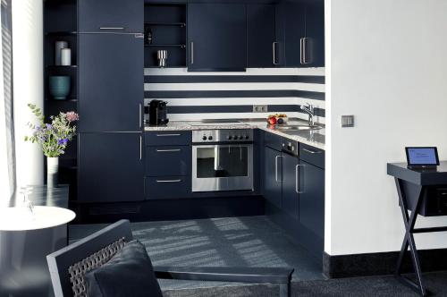 a kitchen with navy blue cabinets and a stove at THE MADISON Hotel Hamburg in Hamburg