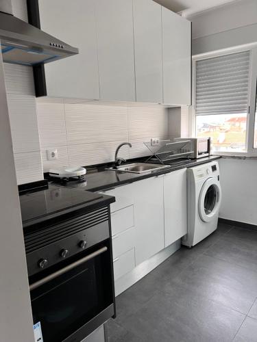 a kitchen with white cabinets and a washing machine at Orquídea in Cacém