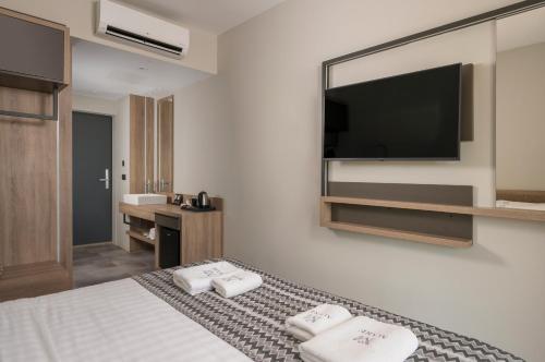a hotel room with a bed and a flat screen tv at Mare Village Hotel in Georgioupolis