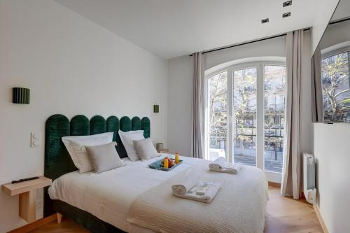 une chambre avec un grand lit avec une grande fenêtre dans l'établissement 343 Suite Jad - Superbe Appartement à Paris, à Paris