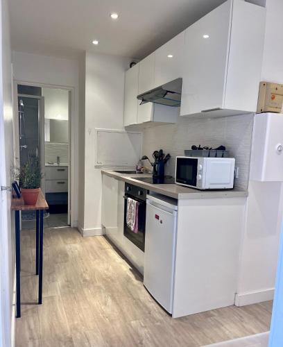 une cuisine avec des armoires blanches et un comptoir dans l'établissement Le Sixt - 2 lit double 1 canapé double - tram & métro, à Villeurbanne