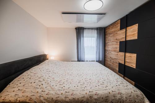 a bedroom with a large bed with a wooden wall at Apartment Trta with Vineyard View in Bistrica ob Sotli