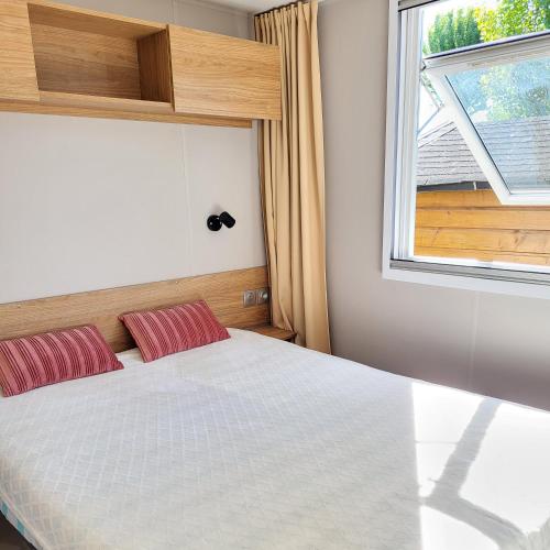 une chambre avec un lit avec des oreillers rouges et une fenêtre dans l'établissement Mobil home gamme luxe 6 personnes camping 5 étoiles, à Saint-Georges-dʼOléron
