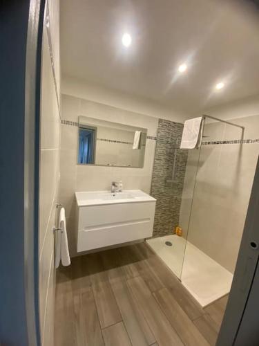 une salle de bain blanche avec un lavabo et une douche dans l'établissement Appartement F4 pour 6 personnes, à Ajaccio