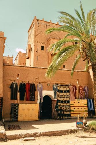a building with clothes and a palm tree in front of it at Afgo Hostel in Ouarzazate