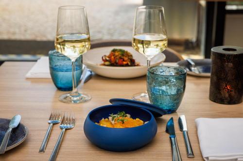 a table with a bowl of food and two glasses of wine at Jupiter Marina Hotel - Couples & Spa in Portimão