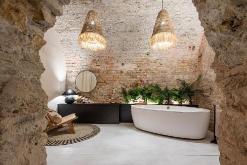 a bathroom with a bath tub and two chandeliers at Aura Spa in Vilnius