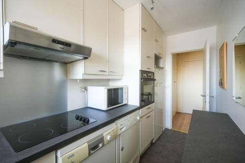 une cuisine avec des armoires blanches et un comptoir noir dans l'établissement Beautifully designed 1BR with King Size bed, à Paris