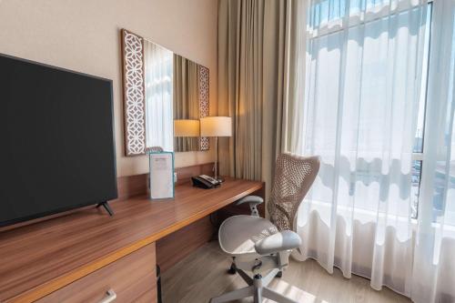 a hotel room with a desk with a television and a chair at Hilton Garden inn Dubai Jumeirah in Dubai