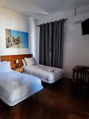 a room with two beds and a window with curtains at Guest House Rooms in Bairro Alto in Lisbon