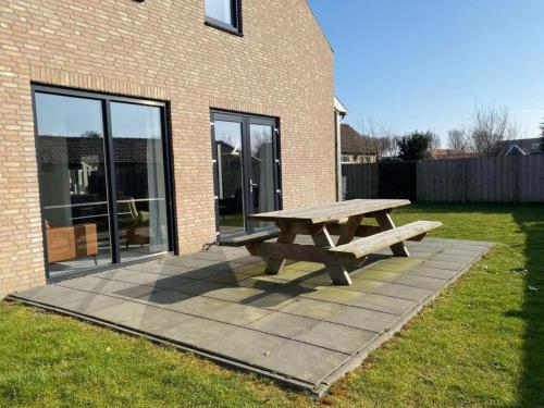 a wooden picnic table in front of a brick building at De Plevieren in Buren