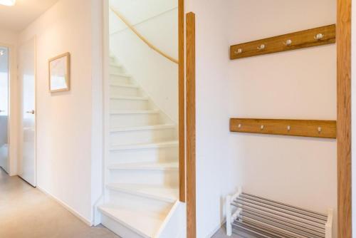 a staircase in a house with white walls and wooden railings at De Plevieren in Buren