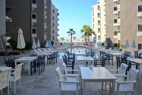 a restaurant with tables and chairs next to a pool at Scylax Hotels Mahmutlar in Alanya