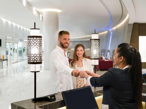 a man and woman shaking hands in a store at Pullman Doha West Bay in Doha