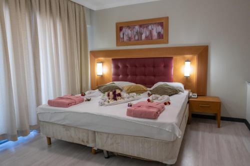 a bedroom with a large bed with pink pillows at Scylax Hotels Mahmutlar in Alanya