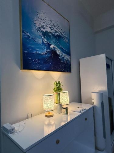 a desk with two lamps and a painting on the wall at JK Suites Cheer B126 in Marilao