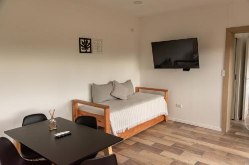 a room with a bed and a table and a tv at Cabañas Valle de los Ciervos in Tandil
