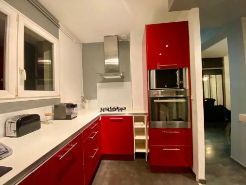 une cuisine avec des armoires rouges et un micro-ondes dans l'établissement Un coin de paradis - 355, à Rouen