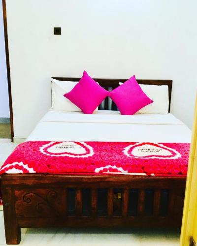 a bedroom with a bed with pink pillows at Adisham village home in Haputale