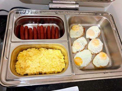 a lunch box with eggs and sausage and other foods at Hôtel Oden Paris Ivry in Ivry-sur-Seine