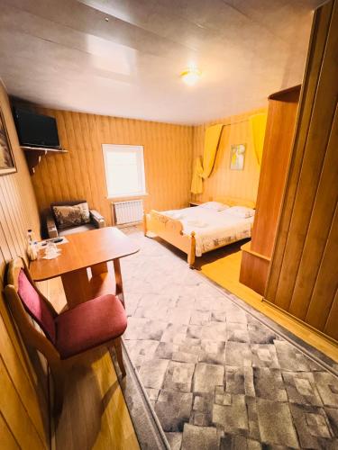 a small room with a bed and a desk and a table at Pid Yavorom in Ivano-Frankivsʼk