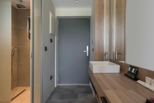a bathroom with a white sink and a tub at Mare Village Hotel in Georgioupolis