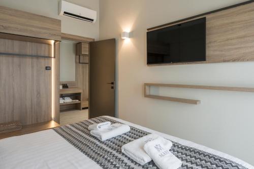 a bedroom with a bed with towels and a flat screen tv at Mare Village Hotel in Georgioupolis