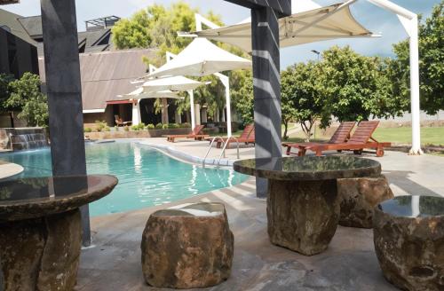 a pool with tables and chairs and umbrellas at Avasta Resort Wijaya Leisure in Anuradhapura