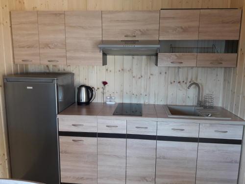 a kitchen with wooden cabinets and a sink and a refrigerator at USTECKA OSADA II Ustka Przewłoka in Ustka