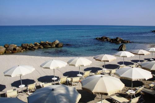 a group of umbrellas and chairs on a beach at Hotel Villaggio Cala Di Volpe in Capo Vaticano