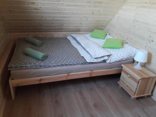 a bed in a wooden room with green pillows at USTECKA OSADA II Ustka Przewłoka in Ustka