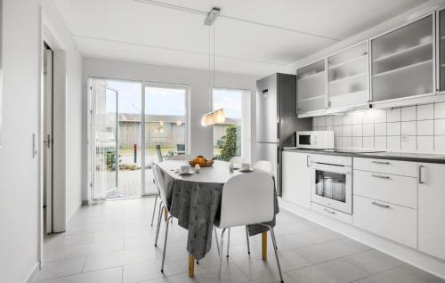 a white kitchen with a table and chairs in it at Holiday Home Næsvej Assens Xii in Assens