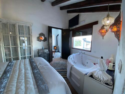 a bedroom with a large bed and a tub at El Capricho, El Escondite de Martina in Setenil
