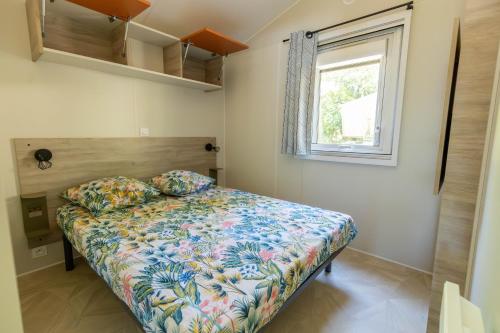 una camera da letto con un letto con un piumone floreale e una finestra di Camping Les Pins de Sel a Saint-Augustin