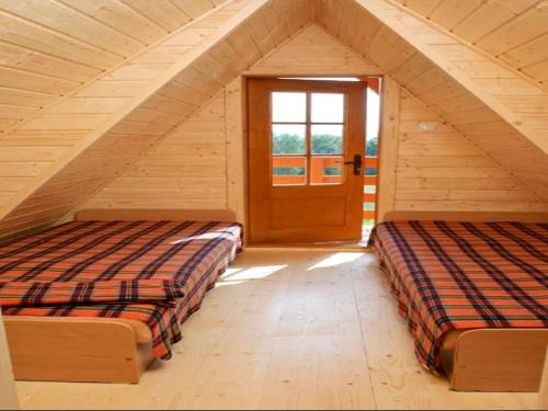 two beds in a attic room with a door at Czocha Palace&Czocha Camping - OR Czocha in Leśna