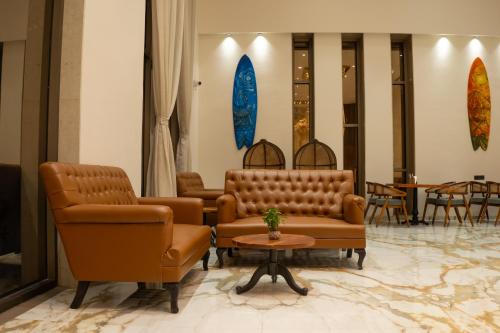a waiting room with brown leather chairs and a table at Pride Elite, Daman in Daman