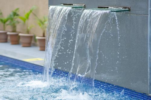 a water fountain in a pool with blue tiles at Pride Elite, Daman in Daman