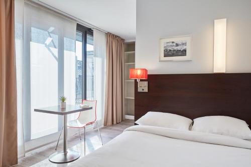 une chambre avec un lit, une table et une fenêtre dans l'établissement Aparthotel Adagio Access Paris Bastille, à Paris