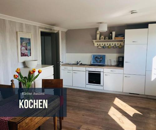 a kitchen with white cabinets and a table in a room at Kleine Auszeit auf Halbinsel Holnis in Holnis