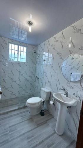 ein weißes Badezimmer mit Toilette und Waschbecken in der Unterkunft Hospedaje Lujoso en Boca Chica in Santo Domingo