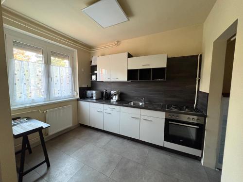 a kitchen with white cabinets and a black appliances at RT Home Vendégház in Szombathely
