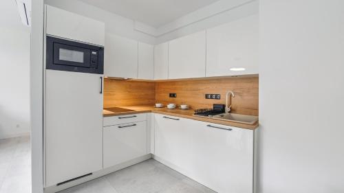a white kitchen with a sink and a refrigerator at Belnihel, Sun & Snow in Hel