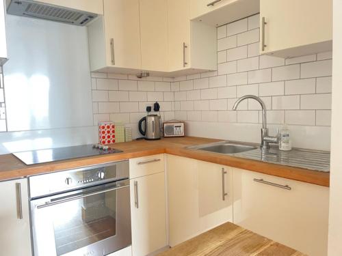 a kitchen with white cabinets and a sink at Sandscape - Eco Beach House - Close to Beach - Pet Friendly in Camber