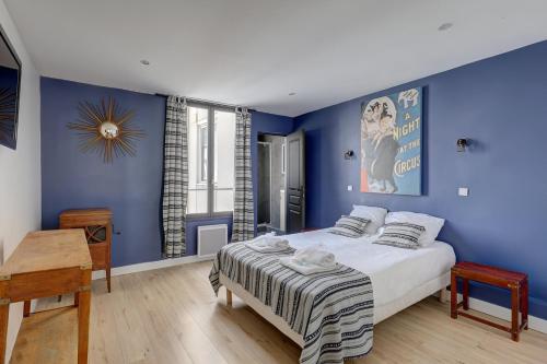 - une chambre avec des murs bleus, un lit et une table dans l'établissement Bluestay 130 - Charmant appartement à Paris 2, à Paris
