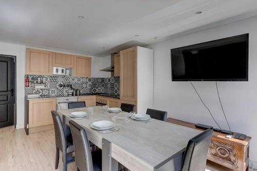 une cuisine avec une table avec des chaises et une télévision au mur dans l'établissement Bluestay 130 - Charmant appartement à Paris 2, à Paris