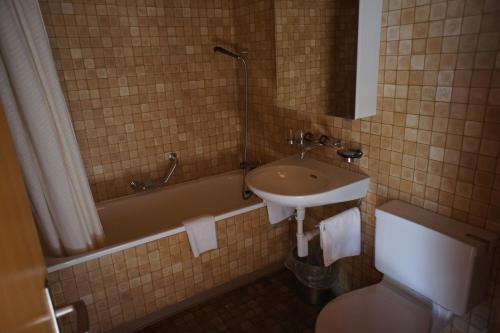 uma casa de banho com um lavatório, uma banheira e um WC. em Hotel Bellary em Grindelwald